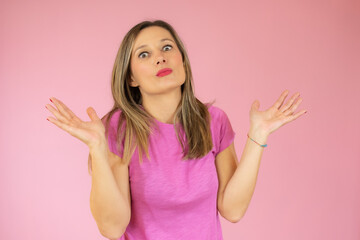 Excited young woman in casual t-shirt posing isolated on pink wall background studio portrait. People lifestyle concept. Mock up copy space.