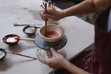 Caucasian female potter in face mask working in pottery studio