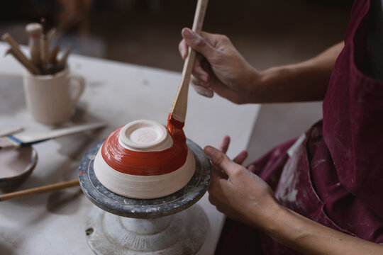 Caucasian female potter in face mask working in pottery studio