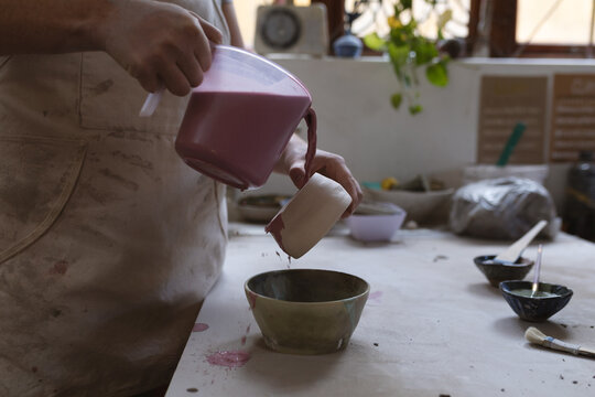 Caucasian female potter in face mask working in pottery studio