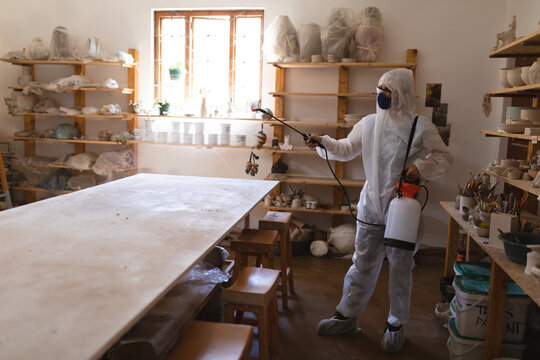 Caucasian male cleaner in protective clothes working in pottery studio