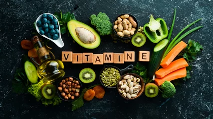Fotobehang Foods rich in vitamin E: pumpkin, broccoli, dried apricots, parsley, avocado and vegetables. The inscription "Vitamin E". Top view. © Yaruniv-Studio