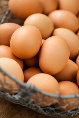 Closeup of brown eggs in metal net basket in natural light. Selective focus - shallow depth of field.