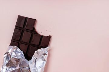 Bited bar of chocolate in foil with crumbs