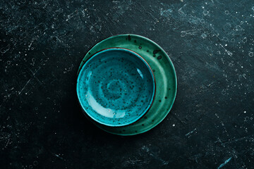 Turquoise plate on a black stone background. Top view. Rustic style.