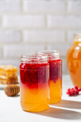 Jar of honey with red chisandra chinensis berries on light table. Healthy food.