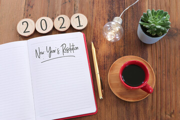 Business concept of top view 2021 goals list with notebook, cup of coffee over wooden desk