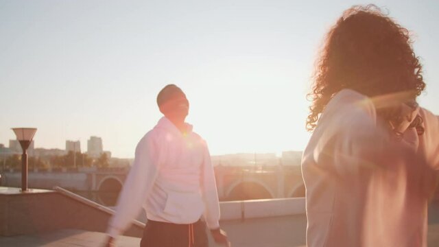 Medium shot of african american man having training outside doing arm circles in front of his female coach on summer morning