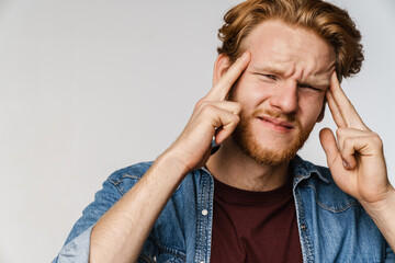 Unhappy redhead guy with headache rubbing his temples