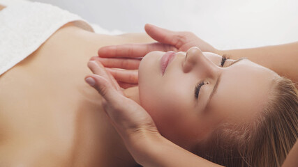 Young, beautiful and healthy woman in massaging salon. Traditional face massage therapy and skin...