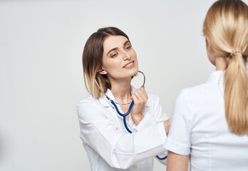 Fototapeta premium A nurse doctor in a medical gown explains something to a patient in a white T-shirt 