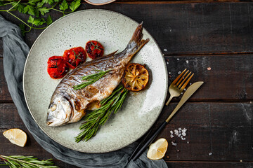 Baked dorado fish on a plate with vegetables on a wooden background top view free space for text