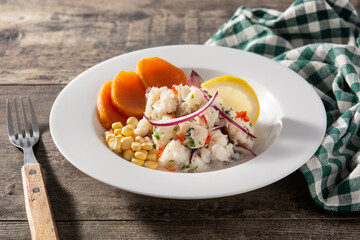 Traditional peruvian ceviche with fish, sweet potato, corn and vegetables on wooden table