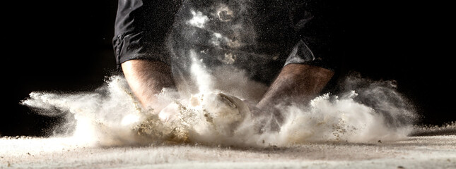 Photo of flour and men hands with flour splash. Cooking bread. Kneading the Dough. Isolated on dark...