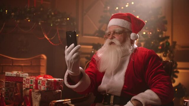old Santa Claus is using modern online communication by internet, calling by smartphone at Xmas holidays