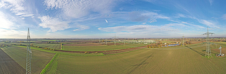 Aerial panoramic picture of a transformer station with many insulators and cables during the day