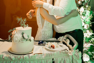Obraz na płótnie Canvas bride and groom at the wedding cut the white wedding cake