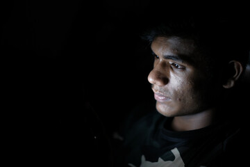 young man sitting on bed using smart phone at night 