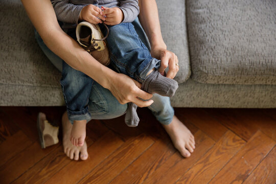 Close up of mother's hands helping baby put socks on