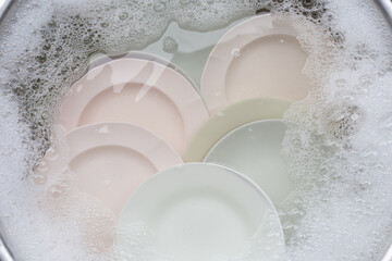 Washing dishes, Close up of utensils soaking in kitchen sink.