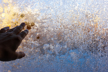 hand and fingers on a background of frozen glass. these are colored frosty patterns