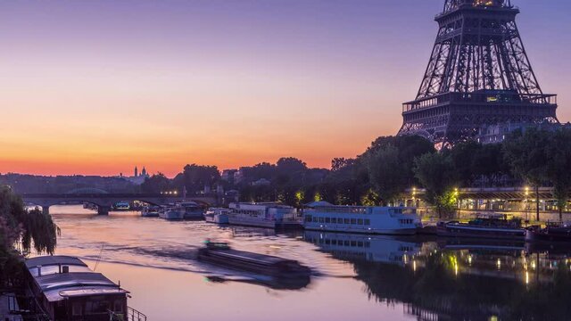 Eiffel Tower and the Seine river night to day transition timelapse before sunrise, Paris, France. Morning view from Bir-Hakeim bridge with reflections on water