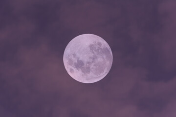 Full moon on the blue sky with clouds.