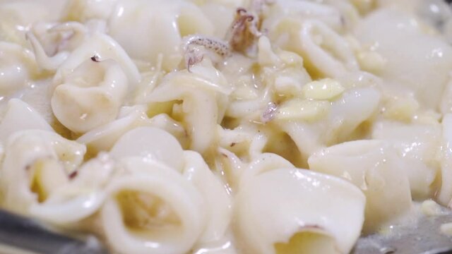 Squit get stir-fried in a pan with garlic and oil. Seafood and asian menu. Slow motion.