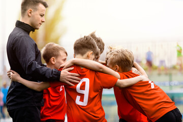 Youth Sports Team. Kids with junior soccer coach huddling in a circle. Boys team in red shirts...