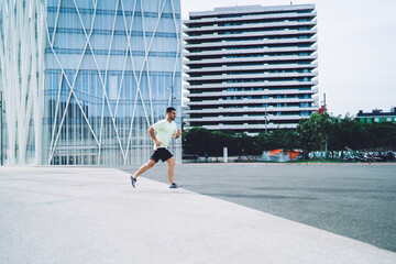 Fototapeta na wymiar Side view of male athlete jogging with endurance enjoying morning training at city street for running, strong man in sportswear have cardio workout training during leisure for intensive practice