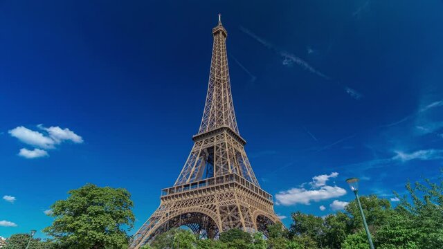 Eiffel Tower from Siene river waterfront in Paris timelapse hyperlapse, France. Blue cloudy sky at summer day with green trees and people walking around