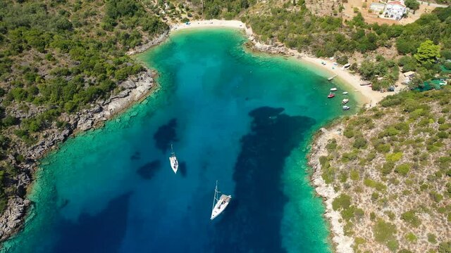 Aerial drone video of turquoise heart shaped paradise sandy beach and bay of Sarakiniko a safe sail boat anchorage in Ithaki or Ithaca island, Ionian, Greece