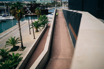 Top view of motivated male jogger running at embankment urban settings training power and endurance, determined sportsman having cardio workout keeping active lifestyle and perfect body shape