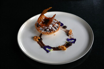 Chocolate dessert cake with berry sauce and almond with decorated