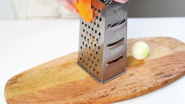 carrots rub on a grater on a cutting wooden board. prepare vegetables for soups, lasagna and other dishes. Home kitchen. 