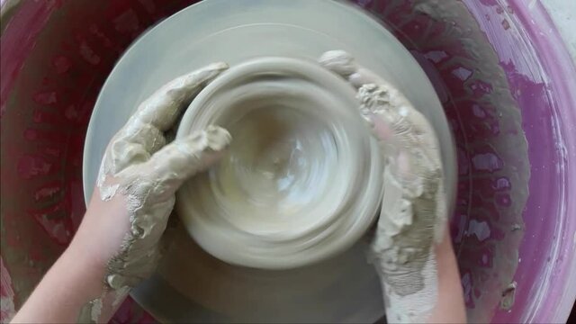 The child is engaged in pottery, sculpts on a potter's wheel. 