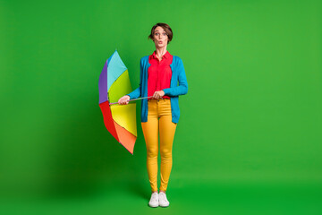 Full length body size photo of shocked girl in glasses keeping colorful umbrella staring isolated...