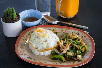 Spicy fried basil leaf with seafood and rice on black table background