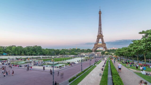 Sunset view of Eiffel Tower timelapse with fountain in Jardins du Trocadero in Paris, France. Long shadows. People walking around. Eiffel Tower is one of the most iconic landmarks of Paris.
