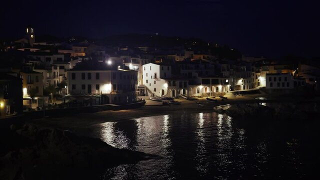 Beautiful Mediterranean village at evening. Night views on a small town on a sea coast. Water and lights of Calella de Palafrugell in Spain. Costa Brava vacation an chill. White houses on the beach..