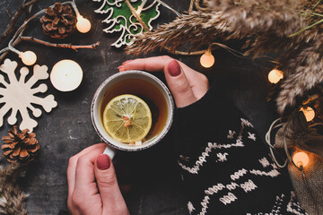 Winter festive food concept. Top view of vintage tea cup. Christmas and New Year background. A woman holds a cup in her hands. Winter mood. Christmas garland and candles © Anastasiia K.
