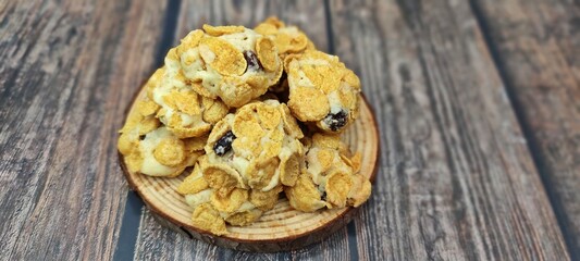 Homemade cornflakes and raisins butter cookies served in wooden tray on wooden table.
