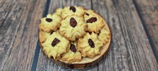 Homemade butter cookies with raisin served in wooden tray on wooden table.