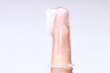 Silicone brush for cleaning the teeth of babies, put on finger, on a light background