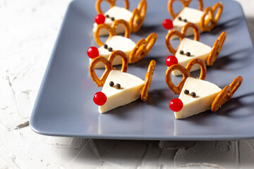 Funny christmas snack in a shapes of deer for kids party. Concept New year food from cheese and pretzels