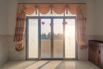 A floor-to-ceiling window, the sun shines into the room