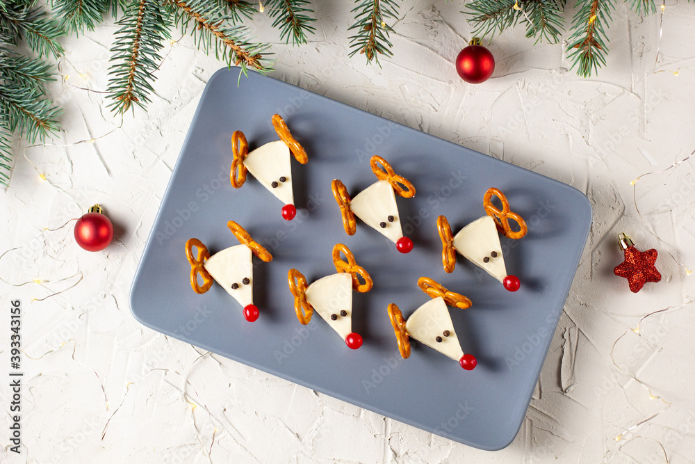 Poster Funny christmas snack in a shapes of deer for kids party. Concept New year food from cheese and pretzels