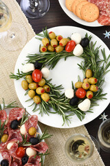  An appetizer of rosemary stuffed with olives with baby mozzarella and cherry tomatoes. Made in the form of a Christmas wreath.