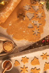 Fototapeta na wymiar Making christmas gingerbread cookies. Raw dough in shape of gingerbread man, christmas tree, star, snowflakes on paper on tray on rustic table with rolling pin. Preparing for baking