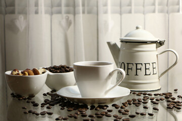Coffee in a white cup and a white coffee pot on a glass table .
